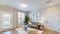 Located on Red Buckeye Drive in Huber Heights, Ohio, this single-floor residence offers a thoughtfully designed open-concept layout that maximizes every square foot. Light wood-tone flooring flows consistently throughout the home, creating a cohesive and warm aesthetic.

The kitchen is a standout feature, showcasing white shaker cabinetry, a white quartz countertop, and a classic subway tile backsplash. A large center island with a matte black sink and pendant globe lighting serves as both a prep space and a casual dining area with bar seating. Black stainless appliances, including a range, over-the-range microwave, and refrigerator, add a bold, modern contrast. A dedicated pantry provides additional storage.

The living room is bright and welcoming, benefiting from large windows and a glass-paned door that flood the space with natural light and offer views to the outdoors. The layout comfortably accommodates a full seating arrangement.

The bedroom is a restful retreat with a natural light source from a window dressed with neutral curtains, access to a closet, and a connecting door to the bathroom. The bathroom features a white shaker vanity with quartz countertop, a rectangular undermount sink, and matte black fixtures, maintaining the home's consistent modern design language throughout.