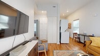 Located at 904 N Garland Ave in Fayetteville, Arkansas, this efficiently designed two-bedroom, one-bathroom home makes excellent use of its compact footprint. Warm hardwood flooring runs throughout, creating a cohesive and inviting atmosphere across all rooms.

The living room is a bright, welcoming space anchored by a pair of French doors that bathe the room in natural light. Elevated ceilings add a sense of openness, while recessed lighting ensures the space is well-lit throughout the day and evening.

The kitchen is thoughtfully appointed with white shaker-style cabinetry, light countertops, and a full suite of stainless steel appliances, including a range, over-the-range microwave, dishwasher, and refrigerator. A practical layout maximizes storage and functionality within the space.

Both bedrooms offer comfortable accommodations with hardwood flooring and windows that allow in natural light. The primary bedroom features a wall-mounted TV setup, while the second bedroom includes a large window with a clean, serene feel.

The shared bathroom is finished with white cabinetry, a vanity with sink, and a shower-tub combination. A built-in storage cabinet above the toilet provides additional organizational space. Throughout the home, a clean, modern aesthetic is maintained with neutral wall tones and thoughtful design details.