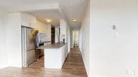 Located at 724–752 Victoria St in New Westminster, BC, this two-bedroom unit offers a well-organized single-floor layout finished with light hardwood-style flooring throughout and a textured ceiling. The open-concept kitchen and living area serves as the heart of the unit, where a white cabinetry kitchen with subway tile backsplash, stainless steel appliances — including a full-size refrigerator, electric range, and built-in microwave — and a peninsula with a dark countertop create a functional and modern cooking space. The kitchen flows seamlessly toward the living room, which is bathed in natural light through a large sliding glass door that opens to a balcony with sweeping views of the Fraser River and the New Westminster skyline. Both bedrooms are well-proportioned, with the primary bedroom offering ample closet space behind mirrored sliding doors. The second bedroom features a window with scenic city and river views, filling the room with natural light. Baseboard heating runs throughout the unit, ensuring year-round comfort. A hallway connects the living areas to a bathroom and provides additional storage. Clean neutral tones and updated finishes give the space a bright, move-in-ready feel.