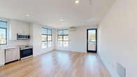 Located at 918 E Thompson Blvd in Ventura, California, this modern studio offers a thoughtfully designed open-concept layout that seamlessly integrates the kitchen and living area. Light wood flooring flows throughout the space, complementing the crisp white walls and recessed lighting that give the interior a clean, contemporary feel. Large black-framed windows flood the space with abundant natural light while framing views of the surrounding neighborhood and nearby mountains. A glass-paneled door opens to a private balcony, further enhancing the connection to the outdoors. The kitchen is well-appointed with stainless steel appliances, including a French door refrigerator, electric range, over-the-range microwave, and dishwasher. White shaker cabinetry, white tile backsplash, and light countertops complete the kitchen's modern aesthetic. A wall-mounted mini-split air conditioning unit provides efficient climate control. The bathroom features a full glass-enclosed walk-in shower finished with classic white subway tile and a skylight window for natural ventilation. Clean lines and a neutral palette make this studio a bright, functional, and stylish space in the heart of Ventura.