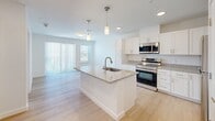 Located at 1418 Frontier Valley Dr in Austin, TX, this efficiently designed one-bedroom, one-bathroom unit offers a thoughtful layout with modern finishes across a single floor. The open-concept kitchen serves as the centerpiece, featuring crisp white shaker cabinetry, granite countertops, a central island with an undermount sink, stainless steel appliances, and elegant pendant lighting overhead. Recessed lighting and light-toned wood-look flooring run throughout, creating a bright, cohesive aesthetic. The kitchen flows seamlessly into the living area, which benefits from natural light through large windows dressed with blinds, enhancing the sense of openness. The bedroom is a comfortable, well-proportioned retreat with a ceiling fan, two windows offering outdoor views of the surrounding Austin landscape, and access to a dedicated closet. The bathroom is finished in a calming palette of soft blue walls, white subway tile surrounding a full soaking tub and shower combination, a granite-topped vanity with white cabinetry, and brushed nickel hardware. Clean lines, neutral tones, and quality materials define the overall ambiance of this well-designed unit, making it a practical and attractive space in the heart of Austin.