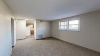 Located at 322 W 65th St in Davenport, Iowa, this single-floor, two-bedroom, one-bathroom unit offers a practical and well-organized layout. The living area is finished with neutral-toned carpet and features a window fitted with blinds that allows natural light to filter through, creating a bright and welcoming atmosphere. Adjacent to the living space, the kitchen is equipped with warm oak-toned cabinetry, generous counter space in an L-shaped configuration, a double-basin sink, and a white electric range with overhead ventilation. Durable wood-look flooring runs throughout the kitchen, adding visual contrast to the softer carpeted areas. The spacious primary bedroom offers notable room to move, complemented by a closet and an additional built-in shelving unit for organized storage. The second bedroom is similarly carpeted, benefits from natural light via a window, and includes its own closet. The full bathroom is cleanly appointed with a vanity featuring wood cabinetry, a toilet, and a tub-shower combination unit, all set on wood-look flooring. Throughout the unit, neutral wall tones and consistent finishes contribute to a clean, cohesive aesthetic well-suited for comfortable everyday living.