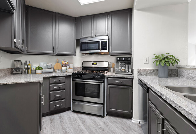 Stone tiled kitchen with stainless steel oven, microwave, and fixtures. - Chateau Encino