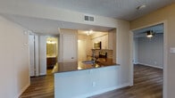 Located at Tides in Dallas, TX 75223, this single-floor 2-bedroom residence offers a well-designed open-concept layout with wood-style flooring throughout. The kitchen is a standout feature, equipped with stainless steel appliances including an electric range and built-in microwave, crisp white cabinetry, a subway tile backsplash, and a dark quartz-style peninsula countertop with an integrated sink — ideal for both cooking and casual dining. The kitchen opens directly to the living area, which boasts vaulted ceilings, a ceiling fan, a white brick fireplace, and a large window that brings in generous natural light. A sliding glass door leads to a private balcony with outdoor views. The bedrooms are spacious and bright, each featuring wood-style flooring, ceiling fans, and ample natural light from windows. The primary bedroom includes a private ensuite bathroom. Both bathrooms are finished with wood-tone vanities, framed mirrors, white countertops, and tiled tub-shower combinations with brushed nickel fixtures. The overall ambiance is clean, modern, and move-in ready, offering comfortable single-level living in a well-appointed Dallas community.
