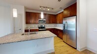 Located at 250 District Dr in Asheville, NC, this well-appointed one-bedroom, one-bathroom residence offers a thoughtfully designed single-floor layout. The open-concept kitchen and living area serves as the heart of the home, featuring rich dark wood cabinetry, granite countertops, and a full suite of stainless steel appliances including a refrigerator with ice maker, electric range, and built-in microwave. A central island with a undermount sink and elegant pendant lighting above adds both function and style, while track lighting illuminates the kitchen workspace. Light hardwood-style flooring flows throughout the main living areas, complemented by ceiling fans that enhance comfort and airflow. Large windows invite generous natural light into the living room, which also provides access to an exterior door. The spacious bedroom features plush carpeting, a ceiling fan, and a sizable window with views to the outdoors. The bathroom offers a granite-topped vanity with dark wood cabinetry and hardwood-style flooring, leading to a separate walk-in shower area. Additional conveniences include a dedicated laundry area, a pantry, and three closets, ensuring ample storage throughout the residence.
