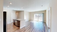 Located at 14306 Sapphire Park Lane in Midlothian, Virginia, this single-floor residence offers a well-designed, open-concept layout ideal for comfortable everyday living. The kitchen serves as a central hub, featuring a granite-topped island with an integrated sink, rich dark cabinetry, stainless steel appliances including a refrigerator, microwave, and range, and recessed lighting overhead. Hardwood-style flooring flows seamlessly from the kitchen through the open living area, which is bathed in natural light from a large sliding glass door that opens onto a private balcony overlooking the surrounding neighborhood. The bedrooms are finished with plush carpeting, ceiling fans, and windows fitted with blinds that provide both light control and privacy. One bedroom includes access to a walk-in closet, adding practical storage. The bathroom features a clean, all-white shower enclosure with brushed nickel fixtures. A dedicated laundry room with full-size washer and dryer hookups and overhead shelving adds everyday convenience. Tile flooring in the utility areas and neutral, warm-toned walls throughout lend the space a cohesive, move-in-ready aesthetic. The overall ambiance is bright, clean, and functional.