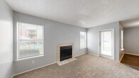 This well-appointed 2-bedroom, 2-bathroom single-floor residence offers a practical and comfortable layout across a compact, efficiently designed footprint. The living room serves as the heart of the home, featuring plush wall-to-wall carpeting, a textured ceiling, soft neutral gray walls, and a tile-surround wood-burning fireplace flanked by multiple windows that fill the space with natural light and offer views to the outdoors. A private entry door provides direct access to the living area. The kitchen is conveniently positioned and connects seamlessly to the living spaces. Both bedrooms are carpeted and well-lit by exterior windows, with the primary bedroom offering generous proportions relative to the overall floor plan. The secondary bedroom features warm hardwood-style flooring and a pendant light fixture. Each of the two bathrooms includes a full tub-and-shower combination — one highlighted by large white subway tiles with marble-accented niches, and the other with a clean white surround. Additional features include two closets for ample storage, a dedicated laundry area, and a hallway connecting the rooms. Throughout the home, consistent light gray walls and neutral finishes create a cohesive, move-in-ready atmosphere.