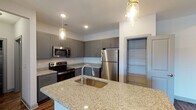 Located at 3973 Woolcock Dr in Myrtle Beach, SC, this single-floor residence offers a well-designed layout with modern finishes throughout. The kitchen serves as a central highlight, showcasing granite countertop surfaces, a large island with an undermount sink, gray shaker-style cabinetry, and a full suite of stainless steel appliances including a refrigerator, range, and microwave. Pendant lighting with a rustic mason jar aesthetic adds character, while wood-look flooring grounds the space with warmth. A dedicated pantry closet provides additional storage convenience.

The living area features rich, dark wood-look flooring, a ceiling fan, and sliding glass doors that open to an outdoor balcony, allowing for natural light and outdoor views. The bedrooms are carpeted for comfort, each equipped with ceiling fans and windows that bring in natural light. The primary bathroom includes a dual-sink granite vanity and a walk-in shower, while a secondary bathroom offers a full tub and shower combination. A dedicated laundry room accommodates a full-sized side-by-side washer and dryer, adding everyday practicality. Throughout the home, neutral gray walls and consistent finishes create a clean, cohesive aesthetic.