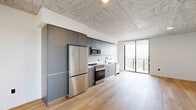 Located at 307 SW 5th St in Fort Lauderdale, FL, this modern 2-bedroom, 2-bathroom residence offers a thoughtfully designed layout with contemporary finishes throughout. The unit is unified by light-toned hardwood flooring and striking exposed concrete ceilings, lending an industrial-chic character to the bright, open interiors.

The kitchen is a standout, outfitted with sleek gray flat-front cabinetry extending to the ceiling, a full suite of stainless steel appliances including a French door refrigerator, gas range, built-in microwave, and dishwasher, all set against clean white countertops and a minimalist black faucet.

Both bedrooms are well-proportioned and bathed in natural light from large floor-to-ceiling windows that frame sweeping panoramic views of the Fort Lauderdale skyline and lush surrounding landscape. The primary bedroom also features access to a private balcony. Black hardware accents on doors and fixtures provide a refined, modern touch throughout.

The two bathrooms are finished with large-format stone-look tile. One features a soaking tub with tiled surround, while the other offers a glass-enclosed walk-in shower with mosaic tile flooring and a backlit vanity mirror. Black matte fixtures add a cohesive, upscale feel to both spaces.