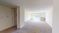 Located at 1503 Hintz Rd in Wheeling, Illinois, this single-floor unit offers a straightforward and functional layout throughout. The living area is generously proportioned, finished with neutral-toned carpet and bright white walls that lend a clean, open feel. A sliding glass door with vertical blinds fills the space with natural light and provides an outdoor view, while a wall-mounted HVAC unit ensures climate control. The adjoining dining or flex area extends the living space further, maintaining the same open, airy atmosphere.

The kitchen features a U-shaped configuration with bold dark cabinetry contrasted against light countertops and white appliances, including a range, dishwasher, and refrigerator. Light tile flooring completes the practical design.

The bedrooms are carpeted and well-lit by windows with horizontal blinds. Each room offers generous closet storage, with bifold doors opening to double closet sections equipped with hanging rods. One bedroom features a connected en-suite bathroom.

Both bathrooms are efficiently designed, each with a white vanity, large mirror with overhead lighting, and patterned tile flooring. The overall ambiance of the unit is clean, bright, and move-in ready.