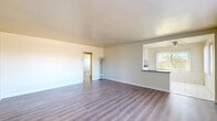 Located at 11700 Glenoaks Blvd in Los Angeles, CA, this 2-bedroom, 1-bathroom single-floor unit offers a practical and comfortable layout. The spacious living room features warm wood-look laminate flooring, neutral-toned walls, and a large window with vertical blinds that invites natural light. A pass-through counter with a dark laminate top connects the living and dining area to the kitchen, creating an open feel between spaces. The galley-style kitchen is well-appointed with white shaker cabinetry, dark countertops, a white gas range, and light tile flooring — providing generous counter and storage space along both walls. Both bedrooms continue the wood-look flooring and are equipped with ceiling fans, large windows with vertical blinds, and built-in closet storage. The primary bedroom features a full wall of built-in white cabinetry, adding notable storage capacity. The bathroom includes a tiled tub-shower combination with sliding glass doors, a wood-toned vanity with a tile countertop, and a frosted window for natural light and privacy. A connecting hallway with four closets adds to the unit's overall storage. The layout is efficient and well-organized throughout.