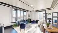 Located in the heart of Downtown Los Angeles on S Spring St, this studio offers a well-designed open-plan layout that combines the living area and kitchenette into a single, efficiently organized space. The unit showcases classic architectural character through bold black crown molding and trim that contrasts sharply against crisp white walls, lending the space a refined, historic aesthetic reminiscent of early 20th-century Los Angeles building design. Elevated ceilings with exposed track lighting add both height and a modern industrial touch, enhancing the overall sense of openness. Large, multi-pane black-framed windows wrap the living area, flooding the space with abundant natural light and framing striking views of the surrounding Downtown LA skyline, including neighboring historic buildings. The compact kitchenette is neatly integrated along one wall, equipped with essential appliances including a microwave, stovetop, and compact refrigerator. The bathroom features classic penny-tile flooring, a standalone vanity, toilet, and a glass-enclosed shower stall, all finished in clean white tones. Dark hardwood-style flooring runs throughout the main living area, grounding the space with warmth and contrast. Overall, this studio combines historic architectural charm with practical urban living in a vibrant Downtown Los Angeles location.