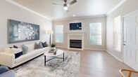 This single-floor residence offers a thoughtfully designed layout with a bright, open living area at its heart. The living room is anchored by a tile-surround fireplace topped with a wall-mounted TV, flanked by multiple windows fitted with white blinds that allow generous natural light to fill the space. Crown molding lines the ceiling, and a ceiling fan adds both function and style. Light-toned hardwood-style flooring runs throughout the main living areas, lending a clean, cohesive aesthetic.

The kitchen is efficiently arranged with a galley-style configuration, featuring white upper cabinetry, gray lower cabinets, and light quartz countertops. Stainless steel appliances, including a refrigerator and range, are complemented by a deep undermount sink with a modern pull-down faucet. The kitchen connects openly to the living and dining areas, supporting an easy flow throughout the space.

The bedrooms are carpeted for comfort, each featuring ceiling fans and ample natural light from well-placed windows. The primary bedroom is notably spacious, offering multiple closets that provide generous storage. Neutral wall tones throughout the entire residence create a calm, versatile backdrop that suits a variety of interior styles.