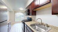 This single-floor residence offers a practical and well-organized layout across three bedrooms, one bathroom, a kitchen, a hallway, and two closets. The living area features neutral-toned carpet and large vertical blinds that allow abundant natural light to filter through, creating a bright and open atmosphere. The galley-style kitchen is equipped with rich dark wood cabinetry, light granite countertops, tile flooring, and black appliances including a refrigerator and gas range, providing ample storage and workspace. The spacious primary bedroom features a ceiling fan, carpeted flooring, and direct access to a built-in closet with shelving, as well as a view into the kitchen area. Additional bedrooms are carpeted and well-proportioned, with one room featuring dual closets with rod and shelf systems, ideal for storage. The full bathroom includes a tiled tub-shower combination, tile flooring, and a vanity with matching dark wood cabinetry. Throughout the residence, neutral gray and beige tones create a clean, cohesive aesthetic. The layout flows efficiently from the entry through the hallway, connecting all rooms with ease and offering a comfortable, functional living environment.