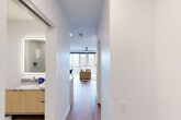 Located at 945 Mid City Dr in Huntsville, Alabama, this modern studio offers a thoughtfully designed open-concept layout that efficiently combines living, sleeping, and dining areas into one cohesive space. Wide-format windows flood the living area with natural light and frame sweeping views of the surrounding Mid City neighborhood, complemented by a sleek ceiling fan overhead and warm hardwood-style flooring throughout.

The kitchen is well-appointed with light wood cabinetry, stainless steel appliances including a refrigerator, range, microwave, and dishwasher, and a tiled backsplash featuring a subtle geometric pattern. A stainless steel undermount sink, quartz-style countertops, and a stylish pendant light over an open shelving unit add both function and character to the space.

The bathroom is finished with large-format tile flooring, a glass-enclosed walk-in shower, and a wood-vanity with an undermount sink and backlit mirror, reflecting the same clean, contemporary aesthetic found throughout the unit. A dedicated closet provides practical storage.

Clean white walls, recessed lighting, and a consistent modern design language tie every area of this studio together, creating a bright, efficient, and visually cohesive living environment in the heart of Huntsville's vibrant Mid City district.