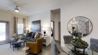 Located at 1971 Willow Loop Way in Knoxville, Tennessee, this single-story residence offers a thoughtfully designed open-concept floor plan that promotes a seamless flow between living, dining, and kitchen spaces. The living room serves as a central gathering area, highlighted by smooth white walls, hardwood-style flooring, and generous natural light streaming in through large windows dressed with elegant curtains. A ceiling fan adds both function and style overhead. The living space comfortably accommodates a full seating arrangement, and an open arched passageway connects to the bedroom wing, enhancing the sense of openness throughout. The kitchen is positioned toward the rear of the layout and features modern cabinetry, quality appliances, and a clean, contemporary design. The floor plan also reveals a dedicated dining area and multiple bedroom spaces, each offering a private retreat. Neutral tones and consistent flooring choices throughout create a cohesive and inviting ambiance. A private entrance and access to an outdoor area further enhance the livability of this well-proportioned Knoxville residence, making it an ideal choice for those seeking comfort and modern design in a single-level layout.