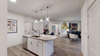 Located at 9445 Bradford Pear Ln NW in Concord, NC, this single-story, 2-bedroom, 2-bathroom residence offers a thoughtfully designed open-concept floor plan. The kitchen serves as a central hub, boasting white shaker cabinetry, granite countertops, a center island with a stainless steel sink, pendant lighting, a mosaic tile backsplash, and a full suite of stainless steel appliances including a French door refrigerator. Wood-look flooring flows seamlessly through the kitchen, dining, and living areas, all finished with crown molding for a polished touch. The living room is bright and inviting, with large windows that allow generous natural light. The dining area connects effortlessly to both the kitchen and hallways, with convenient access to the in-unit laundry room, which accommodates a full-size washer and dryer. The primary bedroom is a comfortable retreat featuring plush carpet, large windows with outdoor views, and a spacious walk-in closet outfitted with wire shelving. Both bathrooms are finished with granite vanities, white cabinetry, and wood-look tile flooring. The overall ambiance is clean, modern, and functional throughout.