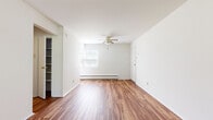 This single-floor unit is thoughtfully arranged across three bedrooms, one bathroom, a kitchen, and a connecting hallway. The layout makes efficient use of space, with hardwood-style flooring flowing through the main living areas, kitchen, and primary bedroom, while carpeting features in the secondary bedrooms for added comfort.

The spacious primary bedroom is the standout room, offering generous proportions, rich hardwood-style flooring, a ceiling fan, a window for natural light, and an open closet with built-in shelving and hanging rod. A second bedroom mirrors this layout with carpet flooring, a ceiling fan, a window with an integrated wall AC unit, a baseboard heater, and a closet. The third bedroom features carpet and an open closet with shelving.

The kitchen is galley-style, fitted with oak cabinetry, a white refrigerator, stove, dishwasher, and a single-basin sink, with a bright window allowing natural light. The full bathroom includes a shower-tub combination and hardwood-style flooring. Throughout, white walls and baseboard heating contribute to a clean, functional, and straightforward living environment.
