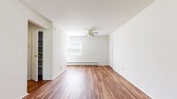 This single-floor unit is thoughtfully arranged across three bedrooms, one bathroom, a kitchen, and a connecting hallway. The layout makes efficient use of space, with hardwood-style flooring flowing through the main living areas, kitchen, and primary bedroom, while carpeting features in the secondary bedrooms for added comfort.

The spacious primary bedroom is the standout room, offering generous proportions, rich hardwood-style flooring, a ceiling fan, a window for natural light, and an open closet with built-in shelving and hanging rod. A second bedroom mirrors this layout with carpet flooring, a ceiling fan, a window with an integrated wall AC unit, a baseboard heater, and a closet. The third bedroom features carpet and an open closet with shelving.

The kitchen is galley-style, fitted with oak cabinetry, a white refrigerator, stove, dishwasher, and a single-basin sink, with a bright window allowing natural light. The full bathroom includes a shower-tub combination and hardwood-style flooring. Throughout, white walls and baseboard heating contribute to a clean, functional, and straightforward living environment.