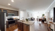 This single-story residence is designed with an open-concept floor plan that connects the kitchen, dining, and living areas into a cohesive, light-filled space. Crown molding and wood-style flooring run throughout the main living areas, contributing to a polished, consistent aesthetic.

The kitchen is a standout feature, equipped with dark espresso cabinetry, granite countertops, a central island with a double sink and dishwasher, and a full suite of stainless steel appliances including a refrigerator, range, and microwave. Recessed lighting and under-cabinet illumination enhance both function and ambiance.

The living room is bright and comfortable, benefiting from natural light through large windows fitted with blinds, a ceiling fan, and generous wall space. The adjoining dining area accommodates a full table and flows naturally from the kitchen island.

The primary bedroom features plush carpet, a ceiling fan, and access to a walk-in closet. Its en-suite bathroom includes a dual-sink vanity and a glass-enclosed walk-in shower. A second bedroom offers soft carpet, natural light, and ample space. The secondary bathroom features a tub-shower combination and wood-style flooring.

A dedicated laundry room houses a full-size washer and dryer, adding practical convenience to the residence.