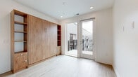 Located at 8770 Galaxy Way in Columbus, Ohio, this efficiently designed studio offers a smart, modern layout across a single floor. The entrance opens into a bright hallway finished with light hardwood-style flooring and crisp white walls, setting a clean, contemporary tone throughout. Recessed lighting runs along the corridor, leading into the main living and kitchen area.

The combined kitchen and living space serves as the heart of the unit. The kitchen is well-appointed with gray shaker-style cabinetry, white quartz countertops, a subway tile backsplash, stainless steel appliances including a range, microwave, and refrigerator, and a peninsula with an undermount sink and pendant lighting overhead. In-unit laundry is conveniently integrated into the kitchen area.

The living space features a built-in Murphy bed system with warm wood-toned cabinetry, open shelving, and integrated drawers — maximizing functionality without sacrificing style. A glass-panel door leads directly to a private balcony, bringing in natural light and outdoor views.

The bathroom is finished with light wood-look flooring, a gray vanity with gold hardware, and clean white walls. Additional storage is provided by a dedicated closet, and a utility room rounds out the layout. The overall aesthetic is bright, modern, and thoughtfully optimized for comfortable living.