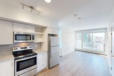 Located in the vibrant Beltline neighborhood of Calgary, this well-designed one-bedroom, one-bathroom unit offers a smart and efficient use of space across a single floor. The open-concept living area seamlessly connects the kitchen, dining, and living zones, creating an airy and cohesive environment filled with natural light from large floor-to-ceiling windows that frame urban city views.

The kitchen is thoughtfully appointed with white cabinetry, a grey tile backsplash, light stone countertops, and a full suite of stainless steel appliances including a refrigerator, electric range, built-in microwave, and dishwasher. Track lighting overhead provides ample task illumination. Light hardwood flooring flows consistently throughout the unit, enhancing the sense of openness and warmth.

The bedroom is a calm, neutral retreat featuring a closet with sliding doors and sunlight filtering in through windows. The unit also benefits from multiple additional closets, offering generous storage throughout. In-unit laundry adds everyday convenience.

The bathroom features a dual-sink vanity with a wide mirror, light stone countertops, and modern cabinetry — a refined and functional space. Clean white walls and a consistent modern palette throughout contribute to a bright, minimalist aesthetic well-suited to contemporary urban living.