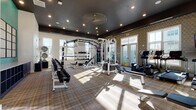 Located at 2200 Silver Crescent Dr in Charlotte, NC, this fitness center is a thoughtfully designed, single-floor facility built to support a wide range of workout routines. The space features a dramatic dark ceiling with recessed lighting that contrasts stylishly with white walls and a plaid-patterned floor, creating a modern and energetic atmosphere throughout.

The strength training area is a standout, anchored by a large multi-functional power rack system complete with barbells, a full set of adjustable dumbbells on tiered racks, medicine balls, kettlebells, resistance ropes, and TRX-style suspension trainers. A vibrant teal accent wall frames a large interior mirror, enhancing the sense of space and making it easy to monitor form during workouts.

A dedicated cardio zone is also present, featuring equipment such as treadmills and an elliptical machine. Geometric-patterned wallcovering adds a decorative touch to one section of the facility, while large windows on multiple walls flood the interior with abundant natural light and offer views of the surrounding community, including an outdoor pool area accessible through French doors. The open layout ensures ample floor space for stretching, functional training, and movement between stations.