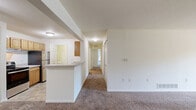 Located at 101 Lake Village Boulevard in Dearborn, Michigan, this single-story residence offers a well-organized layout with one bedroom, two full bathrooms, and a thoughtfully arranged floor plan. The combined living and dining area provides an open, versatile space finished with neutral-toned carpet and crisp white walls, creating a bright and functional environment. A peninsula with a light-toned countertop connects the living area to the galley-style kitchen, which features warm wood cabinetry, light stone-look tile flooring, a stainless steel refrigerator, an electric range, a dishwasher, and a double-basin sink — offering ample storage and counter space in an efficient layout. The spacious primary bedroom is carpeted and benefits from a large window that brings in natural light and views of surrounding greenery. Two full bathrooms serve the unit, each featuring tile flooring, wood vanity cabinetry, and a tub/shower combination with tiled surround. A dedicated in-unit laundry area accommodates a full-size top-loading washer with a wire shelving unit above. Three closets throughout the unit provide generous storage. A hallway connects all rooms in a clean, linear flow, and the entryway includes a private exterior door with a sidelight window.