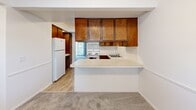 Located at 900 Long Blvd in Lansing, Michigan, this two-story residence offers three bedrooms, two bathrooms, and a practical layout spread evenly across both floors. The main level features a carpeted living room filled with natural light from a large sliding glass door and an adjacent window, accented by classic wainscoting and crown molding. The combined dining and kitchen area showcases warm wood cabinetry, white tile backsplash, light countertops, a peninsula breakfast bar, and durable wood-style flooring. A convenient half bathroom is also located on the main floor. A carpeted staircase with a white-spindle railing leads to the upper level, where all three bedrooms are situated. The spacious primary bedroom includes a walk-in closet with built-in shelving and hanging rods. The additional bedrooms are well-proportioned, each with ample natural light from double windows and individual closets. The full bathroom on the upper level features a wood-toned vanity, tub-shower combination with white tile surround, and a large mirror. Throughout the home, plush carpeting, textured ceilings, and neutral wall tones create a comfortable and cohesive atmosphere. Five closets in total provide generous storage throughout the home.