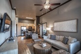 Located on Pujol Street in Temecula, California, this single-story residence offers a thoughtfully designed open-concept layout with warm wood-style flooring flowing throughout the main living areas. The living room is a standout space, distinguished by soaring ceilings with crown molding detail, generous natural light from large windows with exterior views, and ample room for comfortable seating arrangements. A galley-style kitchen is well-appointed with warm yellow cabinetry, dark granite-style countertops, stainless steel appliances including a gas range, built-in microwave, refrigerator, and dishwasher, complemented by a tile backsplash. A kitchen island with bar seating serves as a natural gathering point. In-unit stacked laundry is conveniently integrated nearby. The bedrooms feature plush carpeting, large windows with outdoor views, and generous closet space. The bathrooms are finished with neutral tile surrounds on the tub-shower combinations, light tile flooring, and wood-toned vanity cabinetry with dual sinks in the main bath. A dedicated workspace area and open shelving add functional versatility throughout this well-balanced Temecula residence.