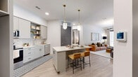 Located at 1010 Singleton Blvd in Dallas, TX, this thoughtfully designed 2-bedroom, 2-bathroom residence offers a seamless blend of modern aesthetics and functional living. The open-concept layout connects the kitchen, dining, and living areas, creating an inviting and cohesive space. The kitchen is outfitted with gray shaker-style cabinetry, quartz countertops, stainless steel appliances, a subway tile backsplash, and a central island with bar seating — illuminated by elegant brass pendant lights. The living area flows naturally from the kitchen and features access to an outdoor space, with light-toned hardwood flooring running throughout. The primary bedroom is a comfortable retreat, complete with a ceiling fan, natural light from a window, and a walk-in closet featuring built-in shelving and wire rack storage. The second bedroom is equally well-proportioned, also featuring a ceiling fan and natural light. Both bathrooms are finished with clean, contemporary tile work, quartz vanities, and gray cabinetry with matte black hardware. One bathroom includes a full soaking tub with a tiled surround. The overall palette of soft whites, warm grays, and light wood tones creates a bright, modern ambiance throughout the home.