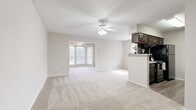 This single-floor residence offers three bedrooms, one bathroom, and a thoughtfully arranged layout that maximizes every square foot. The open-concept living and dining area is a standout feature, anchored by a ceiling fan with light fixture and soft, neutral-toned carpet throughout. A distinctive windowed alcove at the far end of the living area floods the space with natural light and provides views of the surrounding greenery, creating a bright and welcoming atmosphere.

The galley-style kitchen is well-equipped with rich dark wood cabinetry, granite-look countertops, a decorative tile backsplash, and black appliances including a refrigerator, range, and dishwasher. A peninsula counter connects the kitchen to the living area, offering a convenient bar-style serving space.

The primary bedroom is a generously sized retreat with a ceiling fan, plush carpeting, and windows that invite natural light. Additional bedrooms offer comparable comfort and flexibility. The bathroom features matching dark wood cabinetry, a granite-look vanity top, wood-look vinyl flooring, and a full tub-shower combination. A dedicated laundry area adds everyday convenience. Neutral tones and consistent finishes throughout lend the space a clean, cohesive aesthetic.