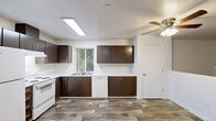Located at 2501 NE 138th Ave in Vancouver, WA, this single-floor, three-bedroom, two-bathroom home offers a well-organized layout with practical finishes throughout. The combined kitchen and dining area serves as a central hub, featuring rich dark-brown cabinetry with modern hardware, white countertops, a stainless steel sink, and white appliances including a range and dishwasher. A large skylight and ceiling fan provide bright, well-ventilated ambiance, while wood-look flooring ties the space together. A dedicated pantry adds extra storage convenience adjacent to the kitchen. The living room is carpeted and opens directly onto a private balcony through sliding glass doors, offering a view of surrounding greenery. Each of the three bedrooms is finished with plush carpet and features natural light from windows, with five closets distributed throughout — including a sliding-door closet in one bedroom. Both bathrooms carry the consistent wood-look tile flooring and dark vanity cabinetry, with one featuring a full soaking tub and shower combination. A dedicated laundry room houses a full-size washer and dryer. The entrance hallway connects all areas efficiently, creating a cohesive and functional flow throughout the home.