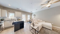 Located in Spring, TX, this two-story home offers a well-designed layout spread across two floors. The main level features an open-concept living, dining, and kitchen area filled with natural light from multiple windows and a glass door leading outdoors. The kitchen is outfitted with stainless steel appliances, white cabinetry, subway tile backsplash, sleek countertops, and a bold dark-finished island that serves as both a workspace and a visual centerpiece. A ceiling fan and light wood-look flooring carry throughout the main level, contributing to a bright, cohesive atmosphere. A hallway connects the living area to the staircase, which leads to the upper floor. Upstairs, two well-proportioned bedrooms each feature ceiling fans, light-toned flooring, and windows with outdoor views. The primary bedroom includes an adjoining closet. Three bathrooms are distributed across both floors, with at least one featuring a full tub-shower combination with tile surround, wood-look flooring, and modern fixtures. A dedicated laundry area with full-size washer hookups and built-in shelving adds everyday convenience. Two closets and two hallways provide ample storage and connectivity throughout the home.