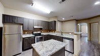 Located at 100 Maglaga Way in Locust Grove, GA, this single-story, 3-bedroom, 2-bathroom home offers a well-designed layout with functional living spaces throughout. The open kitchen is a standout feature, showcasing dark espresso-toned cabinetry, granite countertops, a tile backsplash, stainless steel appliances including a range, dishwasher, and refrigerator, and a central island with additional counter space — all set atop durable wood-look LVP flooring. The kitchen flows conveniently toward the living room area, which features the same LVP flooring and crown molding details. The bedrooms are carpeted for comfort, each equipped with ceiling fans and natural light from large windows. The generously sized primary bedroom includes its own walk-in closet fitted with wire shelving systems, while additional closets throughout the home provide ample storage. The bathrooms feature LVP flooring and a tub/shower combination with decorative tile accents. A dedicated laundry room accommodates a full-size washer and dryer side by side. The home is completed by a hallway connecting all rooms efficiently, making it a practical and comfortable residence.