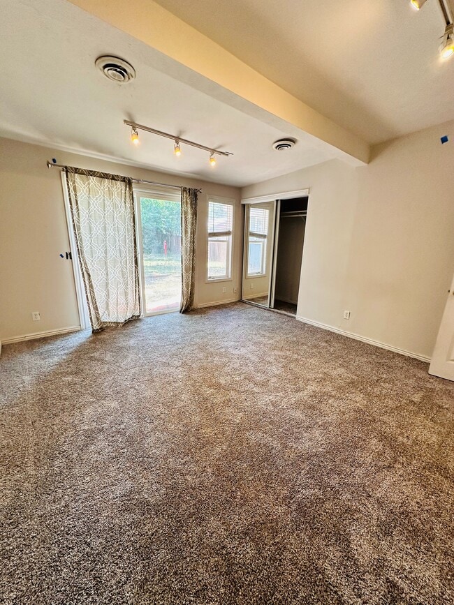 Spacious and inviting room with plush carpeting, modern track lighting, and large windows letting in natural light. - 1385 Yukon Street