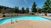 Located at 5680 Hibernia Dr in Columbus, Ohio, this single-floor property offers a comfortable and practical layout well-suited for everyday living. The residence is part of a well-maintained community that provides residents with access to notable shared outdoor amenities. 

A standout feature of the community is the generously sized outdoor swimming pool, which serves as a central gathering space during warmer months. The pool area is complemented by a spacious concrete deck, white lattice fencing that defines the perimeter, and a surrounding landscape of tall, mature evergreen and deciduous trees that provide shade and a sense of natural seclusion. The setting enjoys open sky exposure, making it an inviting space on sunny days.

The broader community environment reflects a suburban residential character, with multi-story neighboring buildings visible in the backdrop and ample green space throughout the grounds. The overall ambiance of the property combines the ease of single-level living with the added benefit of shared outdoor recreational space, making it a practical and appealing option within the Columbus, OH area. The community's landscaping and maintained common areas contribute to a welcoming and livable atmosphere year-round.