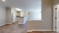 Located at 8200 Riverbirch Dr in Charlotte, NC, this single-floor, three-bedroom, two-bathroom home offers a functional and comfortable layout. The open-concept kitchen and living area form the heart of the space, with the kitchen featuring light wood cabinetry, white appliances, and a peninsula island with a built-in sink — ideal for both cooking and casual dining. Wood-style flooring runs throughout the main living areas, adding warmth and continuity to the design. Crown molding accents the living room, which is highlighted by a classic fireplace with a white-trimmed surround and large windows paired with a glass door that invite generous natural light and provide outdoor access. The bedrooms are carpeted for comfort, with the spacious primary bedroom offering a dedicated walk-in closet equipped with wire shelving. Both bathrooms feature light wood vanities with countertop sinks, tub-shower combinations with white tile surrounds, and wood-style flooring. Neutral gray tones throughout the home create a clean, cohesive aesthetic. Two hallways connect the rooms efficiently, and the overall layout makes practical use of the well-proportioned floor plan.
