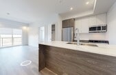 Located in the Edgemont neighbourhood of Edmonton, Alberta, this modern 2-bedroom, 2-bathroom unit offers a thoughtfully designed open-concept layout with clean, contemporary finishes throughout. Light-toned hardwood flooring flows seamlessly across the main living areas, complementing the bright white walls and creating a fresh, airy ambiance.

The kitchen is a standout feature, showcasing a large island with a quartz countertop and rich dark wood cabinetry that provides a striking contrast to the white upper cabinets. Stainless steel appliances — including a refrigerator, electric range, and built-in microwave — complete the functional and stylish cooking space.

The open living area connects effortlessly to the kitchen and benefits from natural light through large windows offering views of the surrounding landscape. Both bedrooms are well-proportioned, with the spacious primary bedroom providing a comfortable private retreat. Each room features the same warm hardwood flooring and large windows that bring in abundant natural light.

The two bathrooms are finished with elegant marble-effect tile flooring. One bathroom includes a soaker tub and single vanity with wood-toned cabinetry, while the second features a walk-in shower with a built-in seat. A dedicated closet adds practical storage to round out this well-appointed unit.