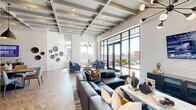 Located at 100 Waddell Plaza Lane in Cary, NC, this single-floor amenity space is a beautifully appointed communal lounge and gathering area designed with a modern, upscale aesthetic. The open-plan layout seamlessly connects multiple functional zones, including a lounge area, dining space, and a kitchenette, all unified by striking chevron-patterned hardwood flooring throughout.

The architecture is defined by soaring coffered ceilings with exposed beams painted in a crisp grey-white palette, adding both depth and visual interest overhead. White-painted brick walls lend a clean, industrial-chic character to the space, while bold, large-scale murals featuring abstract and nautical-inspired artwork serve as dramatic focal points.

The lounge area is anchored by plush navy blue sofas and accent chairs, complemented by stylish pendant and Sputnik-style chandeliers. Floor-to-ceiling steel-framed glass doors and windows flood the space with abundant natural light and provide views of an outdoor terrace. The dining zone features a substantial wooden table with modern seating, ideal for collaborative or social gatherings.

The kitchenette area includes sleek dark cabinetry, white quartz countertops, a tile backsplash, and gold-toned fixtures, adding a refined, contemporary touch. Private booth-style nooks with navy upholstery offer more intimate seating options. The overall ambiance is vibrant, sophisticated, and welcoming.