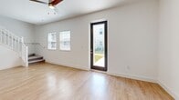 Located at 1898 Zac Street in Kissimmee, FL, this two-story home offers a well-designed layout across two floors. The ground floor features an open-concept living, dining, and kitchen area flooded with natural light. Light hardwood-style flooring runs throughout the main level, complemented by crisp white walls and a ceiling fan in the living space. The modern kitchen is a standout, boasting white shaker cabinetry with black hardware, a white subway tile backsplash, quartz countertops, stainless steel appliances including a refrigerator, range, microwave, and dishwasher, and a central island with pendant lighting overhead. A pantry, utility room, and attached garage round out the first floor. A bright staircase with white railings leads to the upper level, where all four bedrooms are located. The spacious primary bedroom includes a walk-in closet fitted with wire shelving. The three bathrooms feature clean, modern finishes including tile flooring, glass-enclosed showers with white subway tile, and white vanities with dark hardware. Additional closets throughout provide ample storage. The exterior presents a clean stucco facade with a wide concrete driveway, an attached two-car garage, and a fenced yard with established landscaping.