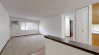 Located at 3050 Old Highway 8 in Roseville, MN, this two-bedroom, one-bathroom residence offers a practical and well-organized single-floor layout. The living room features neutral carpet, a large window that draws in natural light, and a view of the surrounding greenery, creating a comfortable and inviting atmosphere. A half-wall with a dark wood countertop serves as a divider between the living area and the adjacent dining space, which includes warm oak cabinetry with glass-front upper doors and light wood-style flooring that extends throughout the main areas. The galley-style kitchen is efficiently designed with oak wood cabinetry, white countertops, a double sink, and white appliances including a range and refrigerator, all set on light wood-style flooring. The primary bedroom is generously sized, featuring wide windows, soft carpet, and wall-unit air conditioning. Both bedrooms offer built-in closet storage with shelving. The second bedroom is cozy and carpeted with its own closet. The full bathroom includes a wood-toned vanity with a white countertop, wood-style tile flooring, and a tub/shower combination with clean white tile surround. Baseboard heating is present throughout the unit.