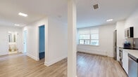 Located at 109 Jameson Ave in Toronto's vibrant Parkdale neighbourhood, this two-bedroom, one-bathroom unit offers a thoughtfully designed single-floor layout. Light wood laminate flooring runs consistently throughout, lending warmth and continuity to the space.

The primary bedroom is a comfortable size and features sliding mirrored closet doors that enhance the sense of space. The second bedroom is bright and airy, with a large window fitted with a roller blind and a baseboard radiator, offering natural light and views of the surrounding greenery. Both bedrooms feature clean white walls and crisp baseboards, creating a neutral and versatile canvas.

The hallway connects the rooms efficiently, contributing to a functional flow throughout the unit. The bathroom is finished in a bright, contemporary style with full white subway tile surrounding the soaker tub and overhead shower. A modern white vanity with a clean-lined sink and chrome fixtures completes the space, all set on light tile flooring.

The kitchen, visible in the layout overview, features white cabinetry, a gas range, and a sink — providing practical functionality. The overall aesthetic throughout the unit is clean, minimal, and move-in ready, making it a well-suited option for those seeking straightforward, comfortable living in central Toronto.
