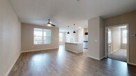 This well-designed single-floor residence offers a thoughtfully planned open-concept layout that seamlessly connects the living, dining, and kitchen areas. The living space features warm hardwood-style flooring, neutral-toned walls, and ceiling fans that enhance comfort and airflow. Natural light flows in through blinded windows, creating a bright and welcoming atmosphere throughout.

The kitchen is a standout feature, anchored by a central island with a built-in sink and white quartz-style countertops. Dark espresso cabinetry provides a striking contrast against the light surfaces, while a full suite of stainless steel appliances — including a refrigerator, range, and microwave — adds a modern, polished look. Stylish pendant lights hang above the island, contributing to the space's contemporary character.

The bedrooms are generously proportioned, each equipped with ceiling fans and windows that invite natural light. One bedroom features plush carpeting, offering a softer, cozier feel, while others continue the hardwood-style flooring found throughout the main areas.

The bathrooms are clean and functional, featuring dark vanity cabinetry with white countertops, large mirrors, and tub-shower combinations with tiled surrounds. The consistent use of light hardwood-style flooring ties the bathrooms cohesively to the rest of the home, resulting in a unified and modern aesthetic throughout the entire space.