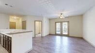 Located in Covington, GA, this well-appointed 3-bedroom, 2-bathroom single-floor residence offers a practical and comfortable layout across a generously sized floor plan. The open-concept kitchen and living area serves as the heart of the home, featuring rich dark wood cabinetry, marble-style countertops with a breakfast bar, and black appliances including a gas range, microwave, and refrigerator. The living area is finished with light wood-style flooring and is anchored by French doors that open to a private balcony, filling the space with natural light and outdoor views. The primary bedroom is spacious, complete with a ceiling fan and a walk-in closet outfitted with wire shelving for ample storage. Its en-suite bathroom includes a standalone shower with modern brushed nickel fixtures and wood-look flooring. The two additional bedrooms feature plush carpeting and ceiling fans, offering comfortable and versatile spaces. The second bathroom includes a shower-tub combination. A dedicated laundry room with wire shelving and washer/dryer hookups adds everyday convenience. Hallways connect the rooms seamlessly, contributing to a cohesive and functional flow throughout the home.