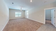 Located at 4212 Napa Oak Dr in Charlotte, NC, this single-floor residence offers a clean, contemporary design with a neutral color palette throughout. The kitchen serves as a central highlight, featuring white shaker-style cabinetry, dark granite countertops, stainless steel appliances including a range, microwave, and French door refrigerator, and a large center island with an undermount sink. Pendant lighting above the island adds a modern touch, while light wood-style flooring grounds the space with a warm, practical finish. The open layout connects the kitchen seamlessly to the living area, which is generously sized and carpeted in soft, neutral tones. A ceiling fan and multiple windows dressed with blinds allow for natural light and comfortable airflow. The bedrooms are carpeted and well-proportioned, each featuring windows that bring in natural light from the surrounding greenery. One bedroom includes direct access to a spacious walk-in closet with wire shelving for ample storage. The bathroom is finished with dual undermount sinks set in dark granite countertops, white cabinetry, brushed nickel fixtures, and a full tub-shower combination. Throughout the residence, white panel doors, recessed lighting, and consistent neutral tones create a cohesive and move-in-ready environment.
