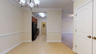 Located at 114 Avalon Park Rd in Mooresville, NC, this single-floor home offers a well-designed layout with consistent, warm neutral tones and quality finishes throughout. The interior is unified by soft cream-colored walls, crisp white baseboards, and crown molding that lend an elegant, cohesive feel to the living spaces.

The kitchen is equipped with rich dark wood cabinetry, black appliances including a refrigerator and range, and light tile flooring. It connects seamlessly to the dining and living areas, which are defined by an open, airy flow. A chandelier adds a decorative touch to the dining space, while the adjacent living areas feature plush wall-to-wall carpeting and ceiling fans with light fixtures for year-round comfort.

The bedrooms are generously proportioned, carpeted for warmth, and benefit from natural light through multiple windows fitted with blinds. One bedroom includes access to a walk-in closet, providing practical storage.

The bathrooms feature tile flooring, rich wood vanities with granite countertops, and tub/shower combinations. A utility corridor off the main bathroom area houses the electrical panel and additional storage behind a louvered door. The overall ambiance is clean, neutral, and move-in ready, offering a comfortable and functional living environment.
