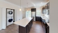 Located at 300 Old Mill Rd in Oakdale, PA, this three-floor residence offers a clean, modern aesthetic with thoughtful finishes throughout. The open-concept main living area features wood-look flooring, crown molding, and multiple windows that flood the space with natural light while offering pleasant outdoor views. A ceiling fan adds comfort to the generous living room.

The kitchen is a standout feature, boasting dark cabinetry, a large center island with a crisp white countertop, pendant lighting, and a full suite of stainless steel appliances including a refrigerator, electric range, microwave, and dishwasher. Wood-look flooring continues seamlessly through this space, and a sliding glass door provides access to an outdoor balcony.

Carpeted bedrooms offer a soft, comfortable feel with neutral walls and ample space. The bathrooms are well-finished with dark vanity cabinetry, white countertops, and wood-look flooring. One bathroom features a walk-in glass-door shower, another includes a soaking tub with classic black-and-white mosaic tile flooring and a window with outdoor views, while a third provides a vanity with a mirror.

An in-unit stacked washer and dryer is conveniently located near the kitchen. The multi-floor layout, visible in the dollhouse view, showcases a staircase connecting the levels and a versatile, functional floor plan throughout.