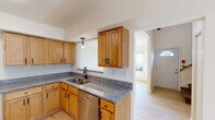 This two-story home offers a well-designed layout that balances comfort and practicality throughout. The kitchen serves as a functional centerpiece, showcasing warm oak cabinetry with black hardware, granite countertops, a stainless steel sink with a modern faucet, and a full suite of stainless steel appliances including a refrigerator, range, over-the-range microwave, and dishwasher. A pass-through window connects the kitchen to the main living area, which features light hardwood-style flooring and a ceiling fan, creating an open and airy feel. A tiled entryway with a front door featuring a transom window provides a welcoming arrival. The bedrooms are carpeted and filled with natural light through large windows that offer pleasant outdoor views, providing a calm and restful atmosphere. The bathrooms are finished with oak vanities and white countertops; one features a dual-sink vanity with a tub/shower combination, while another serves as a convenient half bath. A dedicated laundry area houses a full-size side-by-side washer and dryer. The overall aesthetic is clean and neutral, with consistent warm wood tones, light walls, and modern fixtures throughout, creating a cohesive and inviting living environment across both floors.