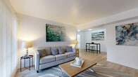 This single-floor, 2-bedroom, 1-bathroom residence offers a thoughtfully organized layout that maximizes its compact footprint. The open-concept living and dining area serves as the heart of the home, featuring light wood-tone flooring, clean white walls, and an arched passageway that connects the two zones seamlessly. The living area is bright and welcoming, with ample room for a full sofa set and coffee table, while the adjacent dining space comfortably accommodates a bar-height table and seating.

The kitchen is efficiently designed, equipped with warm wood cabinetry, a stainless steel electric range with overhead ventilation, a refrigerator, and a single-basin sink — providing all the essentials in a compact, easy-to-navigate space.

The primary bedroom is generously sized, featuring a sliding glass door that fills the room with natural light and provides outdoor views. A dedicated walk-through closet adds practical storage before connecting to the rest of the unit. The second bedroom offers flexibility as a guest room or home office space. The shared full bathroom is finished in clean white tiling with a shower-tub combination, a white vanity, and light wood-tone flooring, maintaining the home's consistent, bright aesthetic throughout.